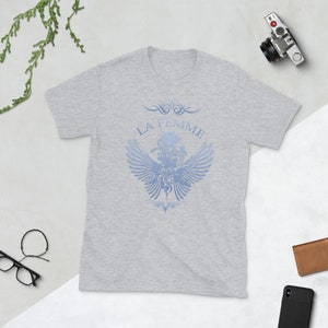 May include: A heather grey t-shirt with a blue graphic design featuring a stylized heart with wings and the text "LA FEMME".