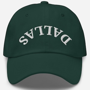 May include: A dark green baseball cap with white embroidered text that reads "DALLAS" in an arc across the front.
