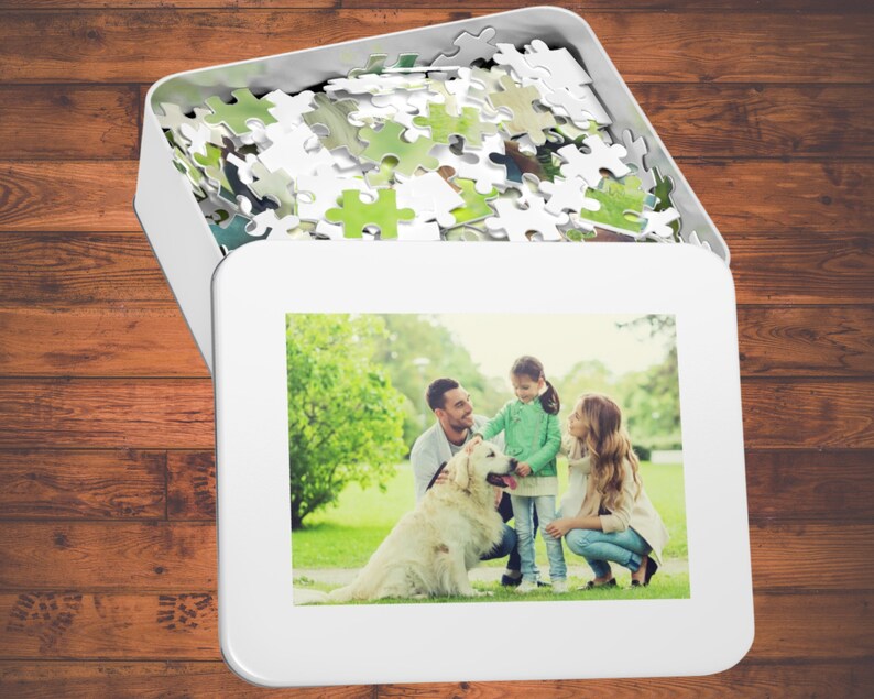 Peut inclure: Une famille de trois personnes, dont un chien, pose pour une photo dans un parc herbeux. La famille sourit et le chien regarde l'appareil photo. La photo est imprim&eacute;e sur une bo&icirc;te de puzzle blanche.
