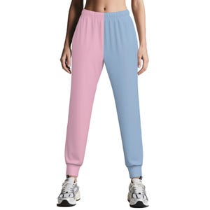 May include: Two-tone sweatpants, split vertically with a light pink and light blue color block design. The pants have a relaxed fit with elastic cuffs at the ankles.