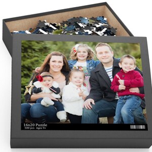 Peut inclure: Une famille de six personnes pose pour une photo devant un sapin de No&euml;l. La famille comprend un homme, une femme et quatre enfants. Les enfants tiennent des cannes en sucre. La photo est imprim&eacute;e sur une bo&icirc;te de puzzle de 16x20 avec 500 pi&egrave;ces. La bo&icirc;te est grise et porte le texte "16x20 Puzzle 500 pcs Ages 9+ ".