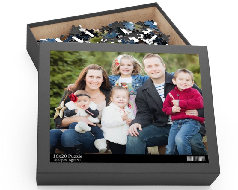 Peut inclure: Une famille de six personnes pose pour une photo devant un sapin de No&euml;l. La famille comprend un homme, une femme et quatre enfants. Les enfants tiennent des cannes en sucre. La photo est imprim&eacute;e sur une bo&icirc;te de puzzle de 16x20 avec 500 pi&egrave;ces. La bo&icirc;te est grise et porte le texte "16x20 Puzzle 500 pcs Ages 9+ ".