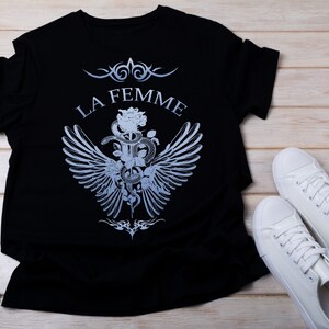 May include: Black t-shirt with a graphic design of a snake wrapped around a rose with wings and the text "LA FEMME".