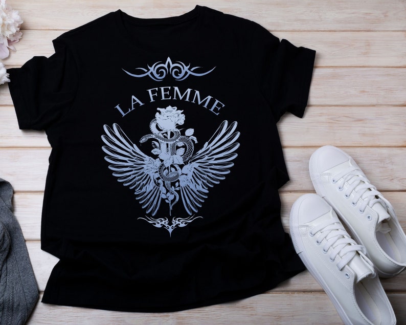 May include: Black t-shirt with a graphic design of a snake wrapped around a rose with wings and the text "LA FEMME".