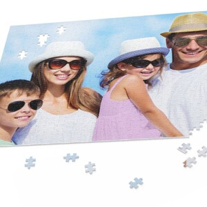 Peut inclure: Une famille de quatre personnes portant des chapeaux et des lunettes de soleil sourit pour une photo. La photo est imprim&eacute;e sur un puzzle avec quelques pi&egrave;ces manquantes.