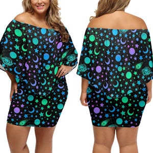 Pode incluir: Vestido preto com ombros de fora e estampa celestial. O vestido apresenta um design repetido de estrelas, luas, planetas e cometas em tons de azul, verde e roxo. Possui uma saia curta e justa e uma parte superior solta e fluida.