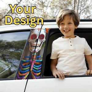 May include: A white car window decal featuring a colorful Day of the Dead sugar skull design. The decal has a vibrant, multi-colored rib cage and floral accents. The text "Your Design" is displayed in yellow above the window.