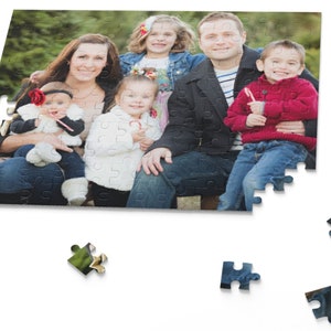Peut inclure: Un portrait de famille montrant un groupe de cinq personnes, dont deux adultes et trois enfants. Les adultes sont assis sur un banc en plein air, tandis que les enfants sont debout devant eux. La famille sourit et regarde la cam&eacute;ra. L'arri&egrave;re-plan est une for&ecirc;t verte et feuillue.