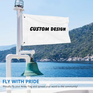 Könnte beinhalten: Eine weiße Flagge mit den Worten "CUSTOM DESIGN" in schwarzer Schrift wird auf einem Boot gezeigt. Die Flagge ist an einer weißen Stange mit einer grünen Glocke darunter befestigt. Der Hintergrund zeigt ein blaues Meer und grüne Berge. Der Text "FLY WITH PRIDE" steht unten.