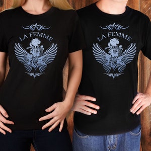 May include: Two black t-shirts with a graphic design of a rose, snake, and wings. The text "La Femme" is printed above the graphic.