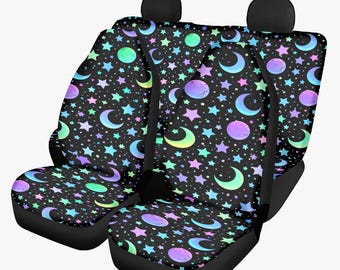 May include: Set of two black car seat covers with a celestial pattern. The design features colorful stars, moons, and planets in shades of blue, green, purple, and pink. The seat covers have black headrests and a black base.