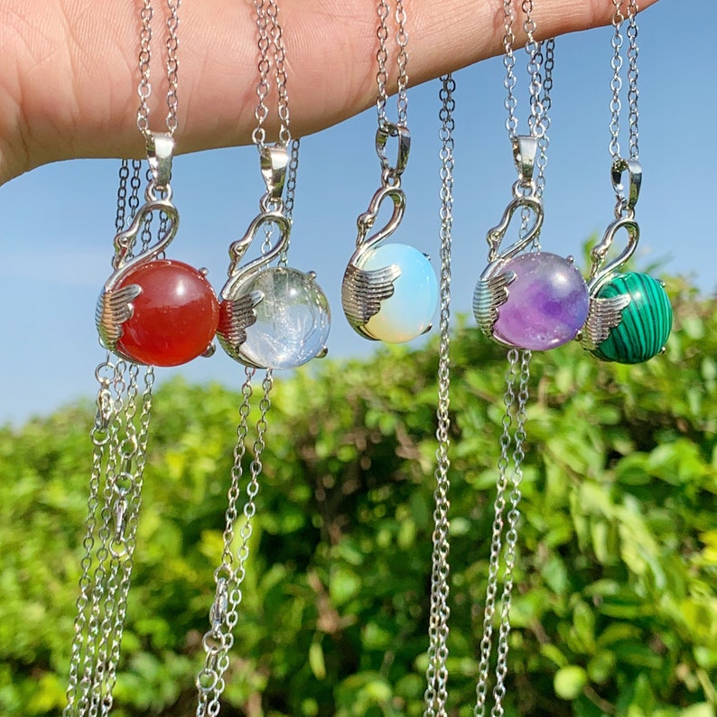 Pode incluir: Cinco colares de prata com pingentes de pedras preciosas de diferentes cores. Os pingentes t&ecirc;m a forma de cisnes e apresentam pedras preciosas vermelhas, transparentes, brancas, roxas e verdes.