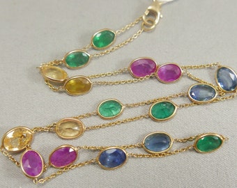 May include: A gold chain necklace with oval-shaped gemstones in various colors, including green, blue, pink, and yellow.