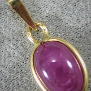 Peut inclure: Un pendentif en or avec une pierre précieuse ovale rose. Le pendentif a un design simple avec une finition lisse et polie.