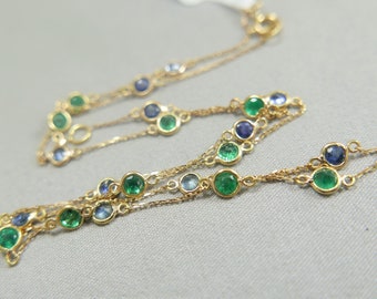 May include: A gold chain necklace with green and blue gemstones. The necklace is made of multiple strands of chain with small round gemstones.