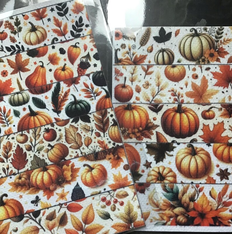 May include: Decorative washi tape featuring a fall harvest theme. The tape showcases a repeating pattern of pumpkins, leaves, and berries in shades of orange, brown, and green against a cream background. The tape is perfect for scrapbooking and crafting.