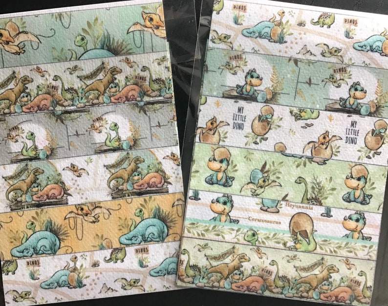May include: Two sheets of decorative washi tape featuring various dinosaur illustrations in shades of green, brown, and blue. The tape includes text that reads "My Little Dino" and "Hey Y'all". The designs include baby dinosaurs, eggs, and foliage.