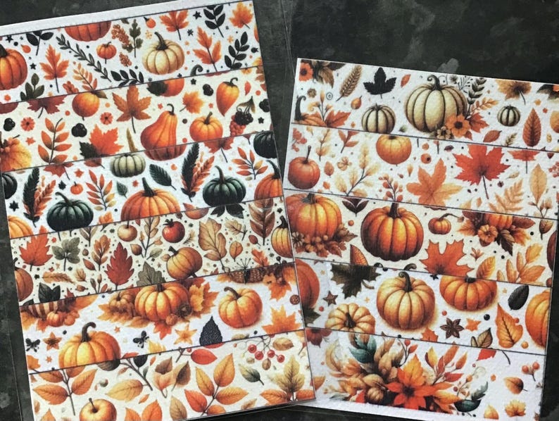 May include: Two sheets of decorative paper with a repeating pattern of pumpkins, leaves, and berries in shades of orange, brown, and green on a white background. The design evokes a fall or harvest theme.