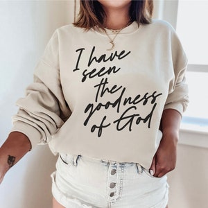 Może przedstawiać: Beżowa bluza z nadrukiem "I have seen the goodness of God" w kolorze czarnym.