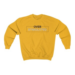 Może przedstawiać: Ż&oacute;łta bluza z napisem "OVER STIMULATED" w czarnym prostokącie.