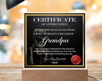 Peut inclure: Un certificat d'appréciation noir et or avec le texte "Certificat d'appréciation" et "Le meilleur grand-père du monde". Le certificat porte un sceau rouge avec le texte "Meilleur grand-père".