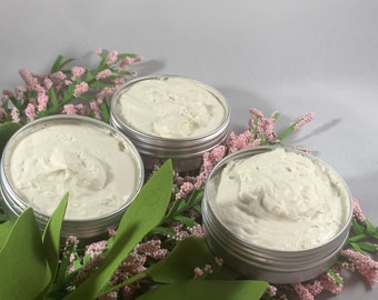 Puede incluir: Tres latas plateadas llenas de una sustancia blanca y cremosa. Las latas están rodeadas de hojas verdes y flores rosas.