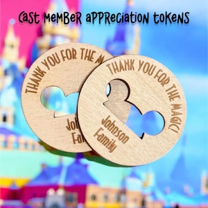 Op de afbeelding: Twee houten tokens met een Mickey Mouse-ooruitsnijding. De tokens zijn gegraveerd met de tekst "Bedankt voor de magie!" en de namen "Johnson Family" en "Jol Family".