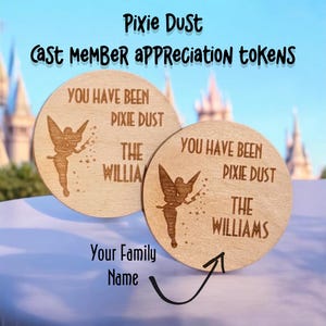 May include: Two round wooden tokens with a Tinkerbell design and the text "You have been pixie dusted The Williams" on each. The tokens are for cast member appreciation.
