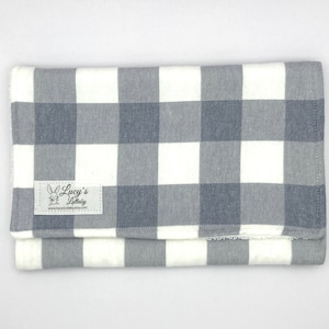 May include: Grey and white checked burp cloth with a white label that says "Lucy's Littlaly" and a website address.