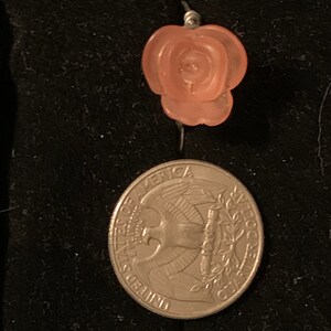 May include: A pink rose-shaped bead charm with a silver wire loop.