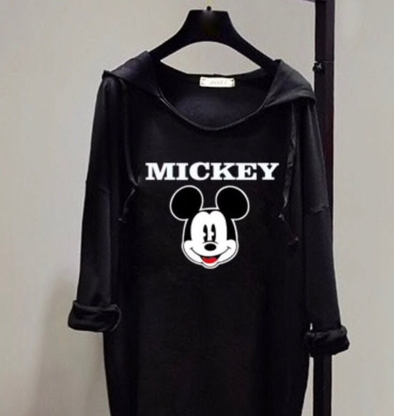 Puede incluir: Sudadera con capucha negra con un gr&aacute;fico de Mickey Mouse blanco y la palabra "MICKEY" impresa en blanco.