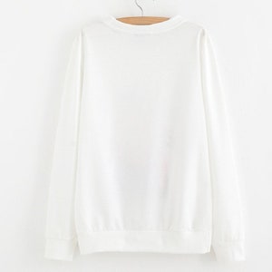 Peut inclure: Sweat-shirt blanc &agrave; manches longues avec un col rond.
