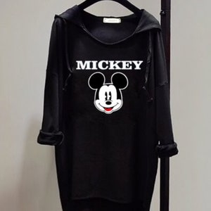 Puede incluir: Sudadera con capucha negra con un gr&aacute;fico de Mickey Mouse blanco y la palabra "MICKEY" impresa en blanco.