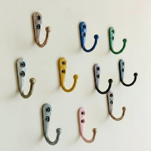 Peut inclure: Ensemble de neuf crochets muraux en métal de différentes couleurs : bronze, bleu, vert, argent, jaune, noir et rose. Chaque crochet, de forme incurvée, est fixé avec des vis, offrant une solution de rangement décorative et fonctionnelle.