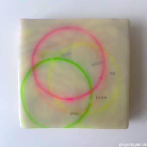 Può includere: Un quadrato bianco con tre cerchi sovrapposti disegnati in rosa neon, verde e giallo. I cerchi hanno le parole "does", "want", "to", "love" e "you" scritte al loro interno.