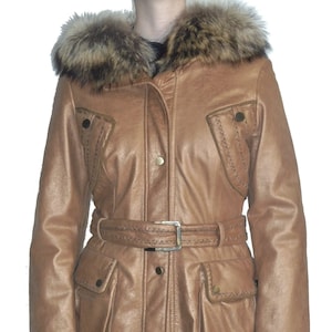 Op de afbeelding: Een bruin leren jack met een bontkraag en een riem. Het jack heeft decoratieve stiksels en zakken.