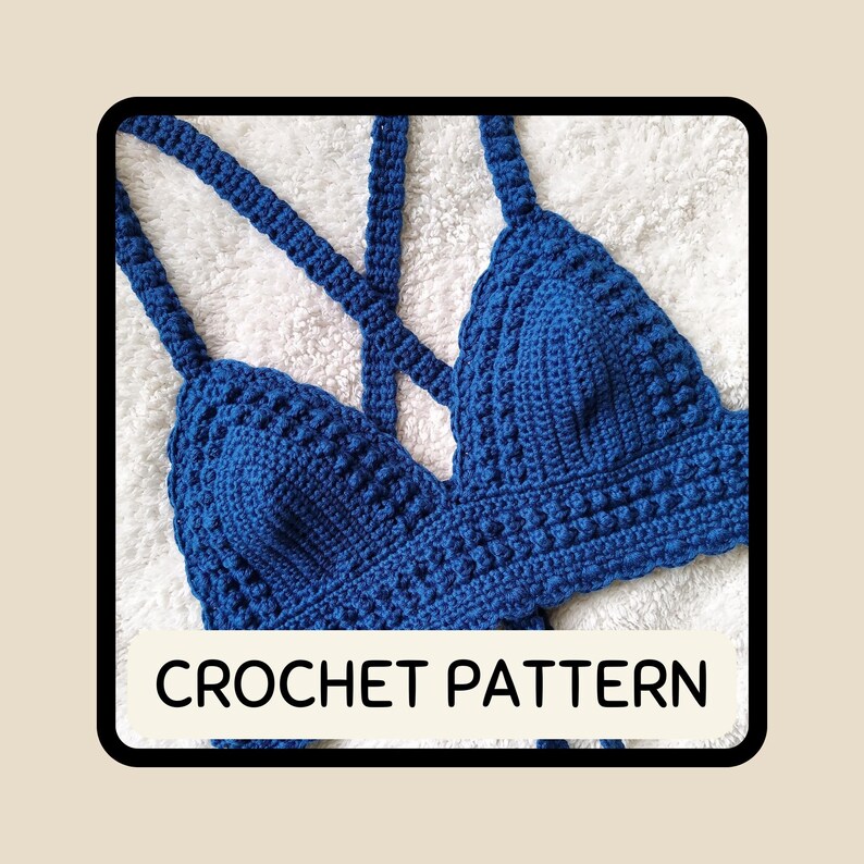 May include: A handmade, blue crochet top with a criss-cross back design. The top features a textured stitch pattern and straps. The text "CROCHET PATTERN" is displayed in a white rectangle at the bottom of the image. The top is displayed on a white, textured surface.