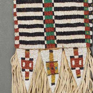 Peut inclure: Une bourse en perles avec une frange en cuir. La bourse est décorée de perles noires, blanches, rouges et vertes en un motif géométrique.