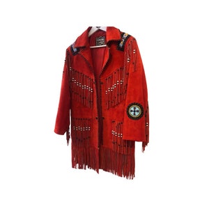 May include: Red suede jacket with fringe and beading details. The jacket has a Native American inspired design with a beaded cross on the sleeve. The label reads "Genuine Leather".