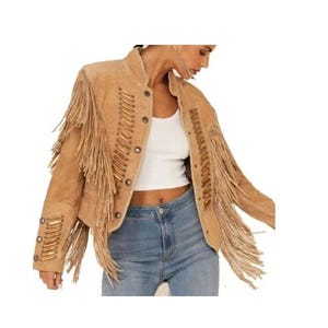 May include: A tan suede jacket with long fringe detailing on the sleeves and back. The jacket has a button-up front and decorative stitching. The collar is a stand-up style. The jacket is a neutral color and is suitable for various outfits.