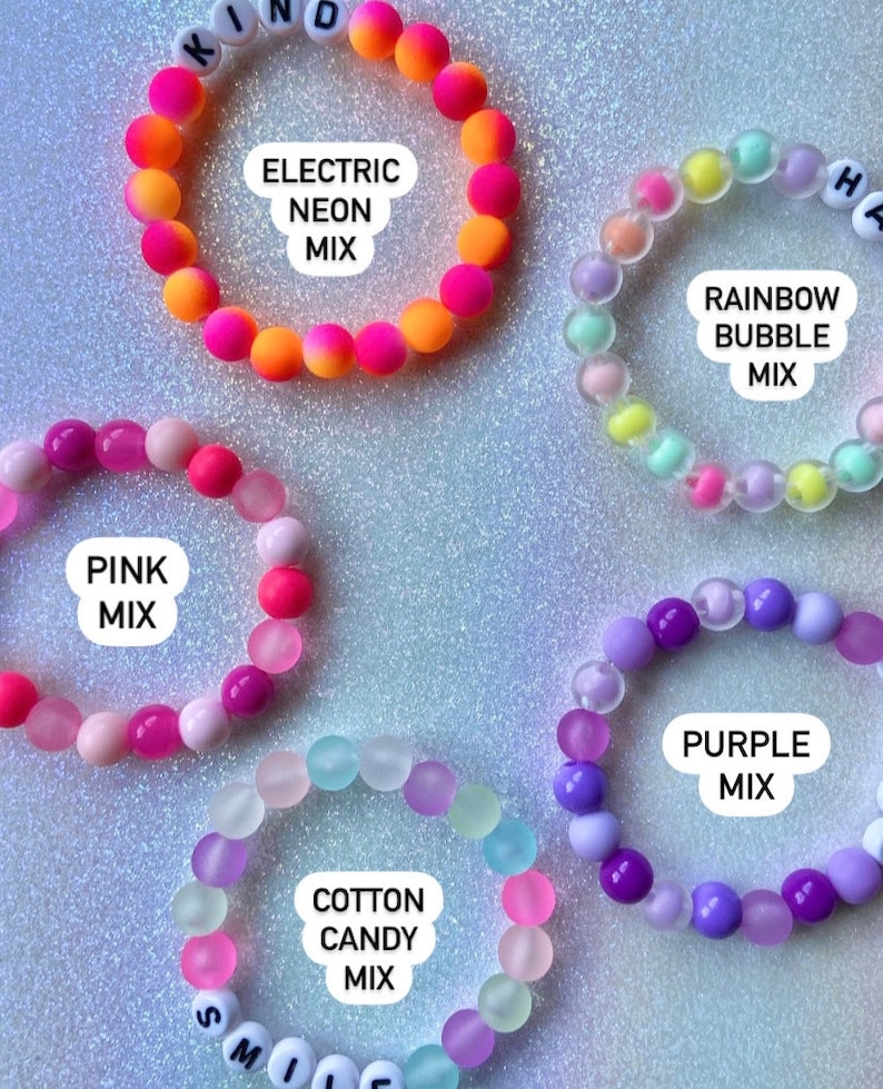 Puede incluir: Seis pulseras de cuentas coloridas con diferentes combinaciones de colores y texto. Las pulseras est&aacute;n hechas de cuentas peque&ntilde;as y redondas y tienen diferentes combinaciones de colores, incluyendo rosa, morado, azul, verde, amarillo y naranja. Las pulseras tienen texto en ellas, incluyendo "KIND", "ELECTRIC NEON MIX", "RAINBOW BUBBLE MIX", "PINK MIX", "COTTON CANDY MIX" y "PURPLE MIX".