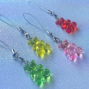 May include: Four gummy bear phone charms with silver chains. The gummy bears are red, pink, yellow, and green.