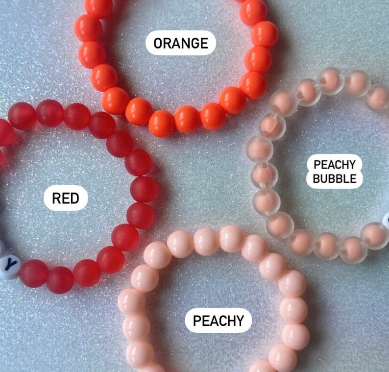 Puede incluir: Cuatro pulseras de silicona en diferentes colores: rojo, naranja, melocot&oacute;n y transparente. Las pulseras est&aacute;n etiquetadas como "ROJO", "NARANJA", "MELOCOT&Oacute;N" y "BURBUJA DE MELOCOT&Oacute;N".