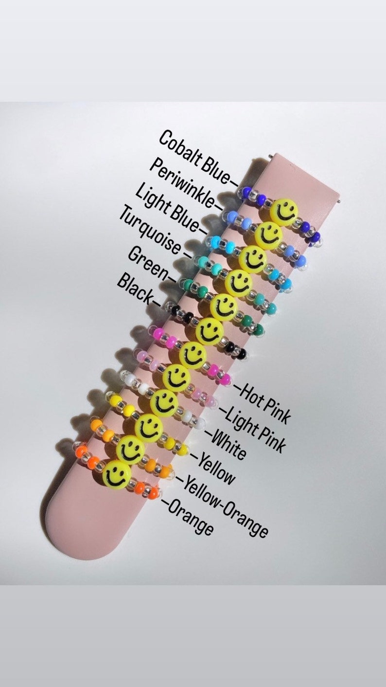 May include: A set of 12 colorful beaded bracelets with a smiley face charm. The bracelets are in the colors: cobalt blue, periwinkle, light blue, turquoise, green, black, hot pink, light pink, white, yellow, yellow-orange, and orange.
