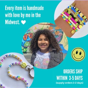 May include: A young person wearing a white t-shirt with a floral design and a denim jacket. The person is smiling and looking at the camera. The person is standing in front of a colorful mural. The image also shows a colorful beaded lanyard with a smiley face charm. The text "ORDERS SHIP WITHIN 3-5 DAYS (supply orders 1-2 days)" is visible at the bottom of the image.