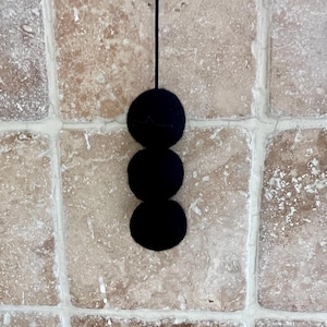 May include: A black hanging mobile with three round felt balls.