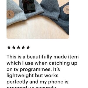 May include: Three gray felt phone stands with a black phone propped up on one of them. The stands are triangular in shape and have a small brown tag with the text "Etsy Shop" on them.