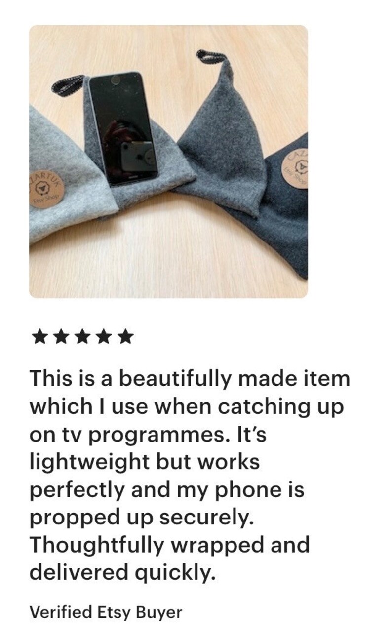 May include: Three gray felt phone stands with a black phone propped up on one of them. The stands are triangular in shape and have a small brown tag with the text "Etsy Shop" on them.