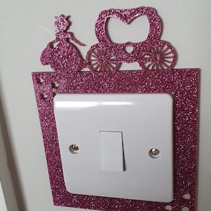 May include: A pink glitter light switch cover with a princess and carriage cutout design.