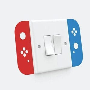 May include: A white light switch with a red and blue Nintendo Switch controller design. The controller design has a white circle, four white dots, and a white square on the red side. The controller design has a white circle and four white dots on the blue side.